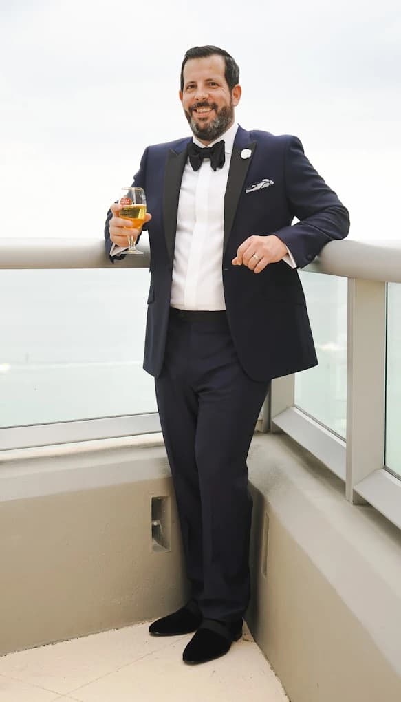 Man wearing a custom navy tuxedo with classic peak lapels and a crisp white dress shirt at a formal event
