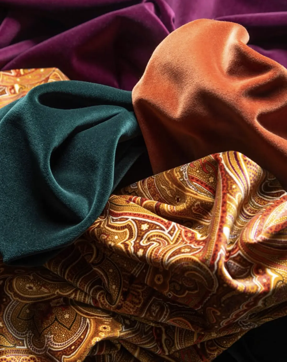 Dormeuil velvet and paisley silk fabrics in magenta, teal, and burnt orange with rich draping