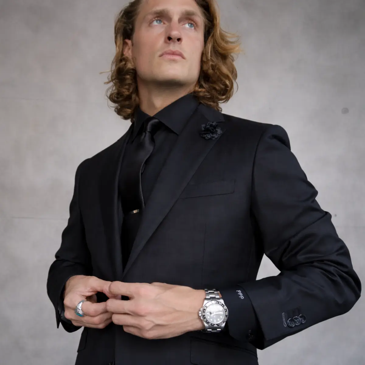 Client in a custom black peak-lapel suit with tie bar and floral lapel pin, styled by Bespoke By CB for a formal event wardrobe