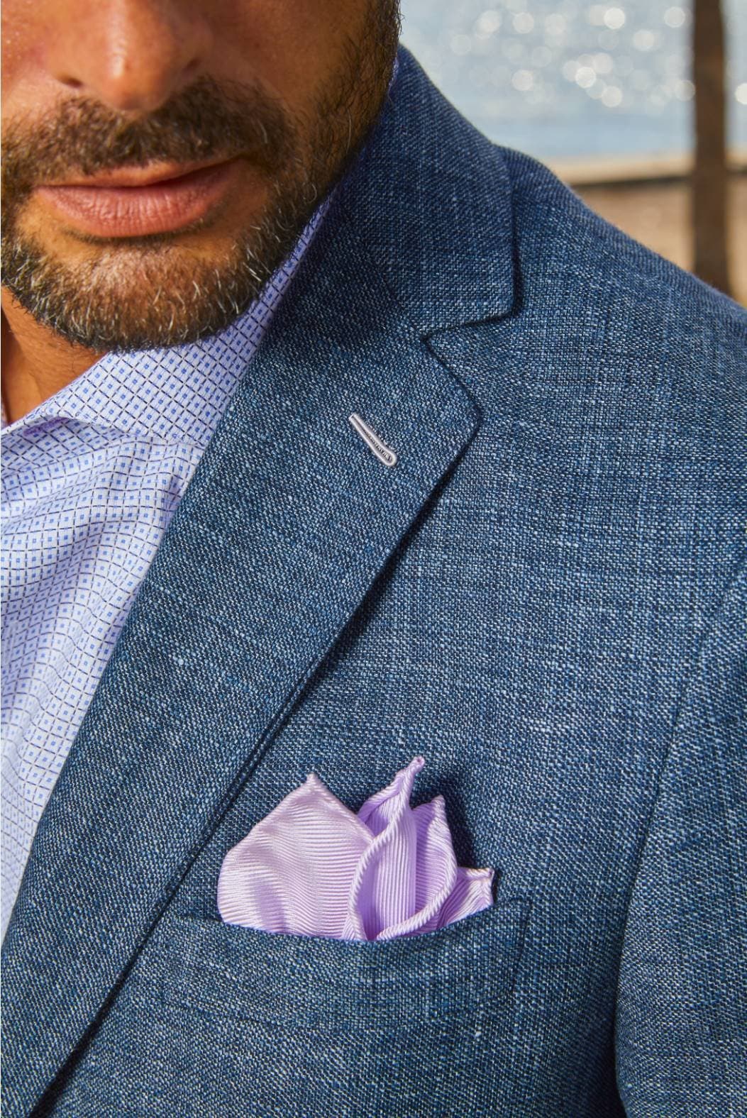 Close-up of a lavender pocket square in a custom navy suit jacket breast pocket