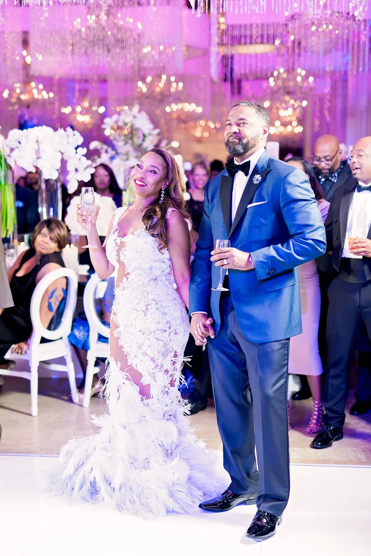 Bride in white feather mermaid gown and groom in cobalt blue peak-lapel tuxedo at wedding reception