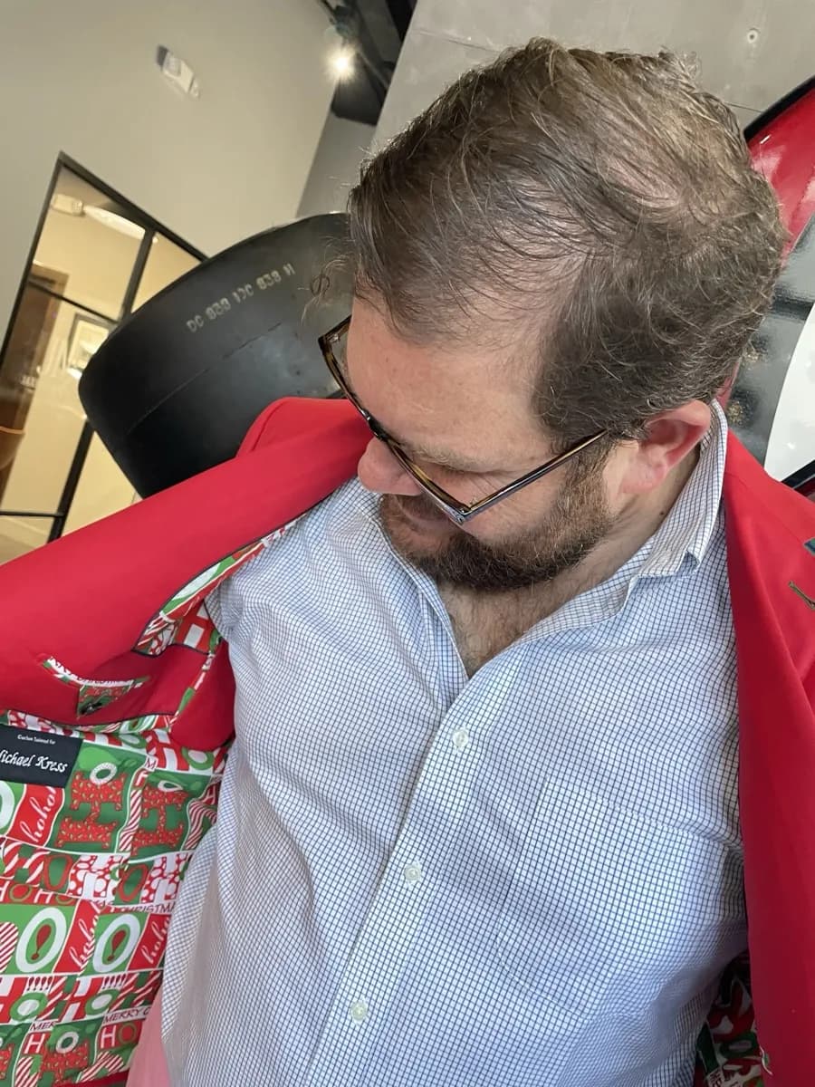 Man wearing red suit jacket with custom Christmas lining featuring HO HO HO and candy canes, Bespoke By CB Miami
