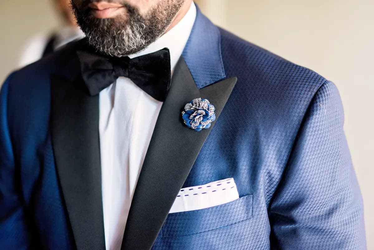 Close-up of blue patterned tuxedo jacket with black satin peak lapels and velvet bow tie