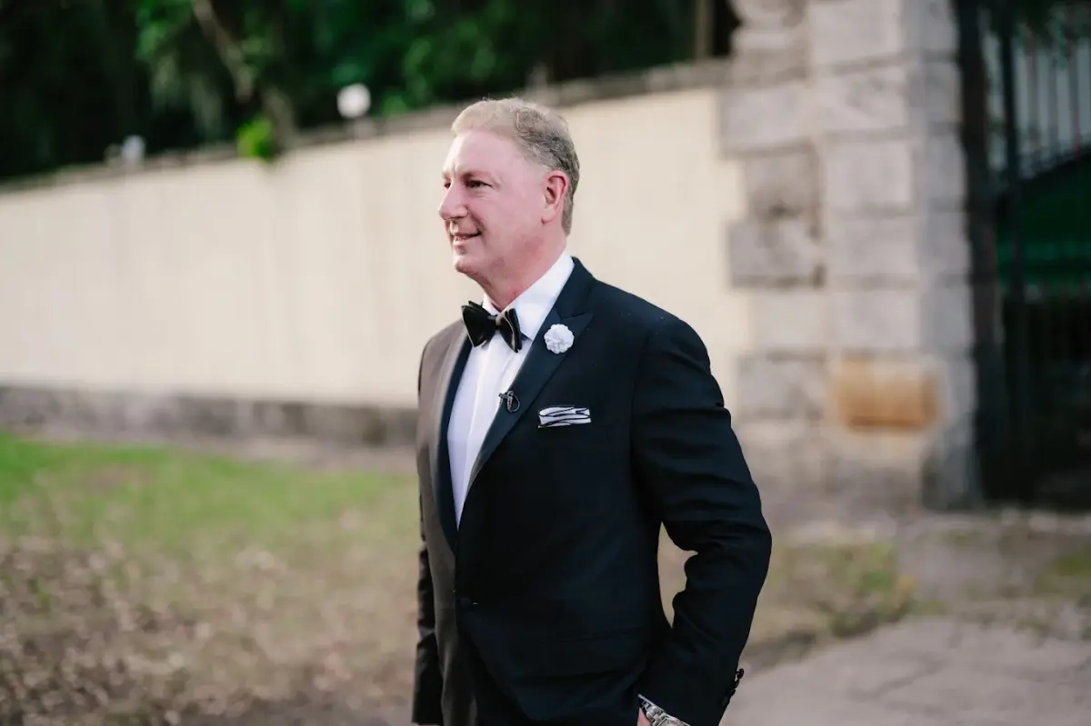 Father of the bride in black tuxedo with satin lapels and pocket square, outdoor ceremony